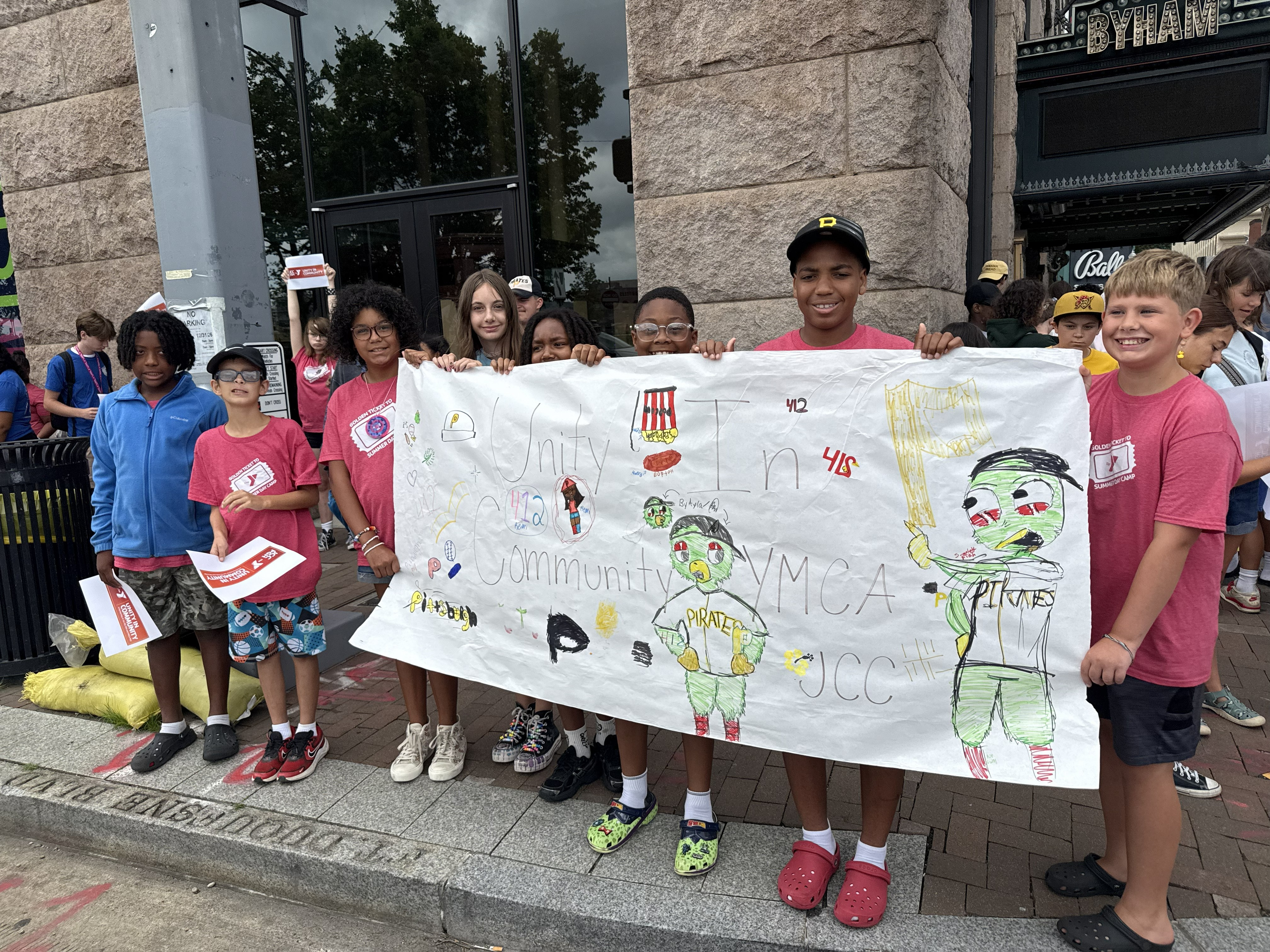 Campers holding a "Community in Unity" banner before marching across the Clemente Bridge