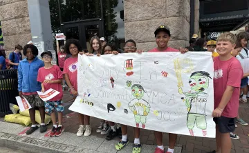 Campers holding a "Community in Unity" banner before marching across the Clemente Bridge